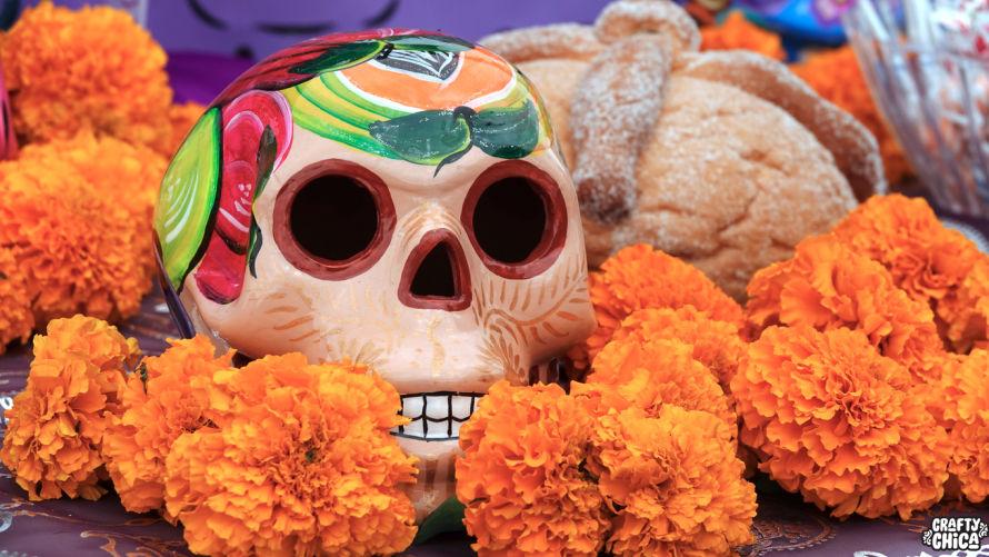 Orange marigolds surrounding a decorated skull and pan de muerto for Day of the Dead